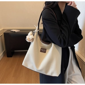 Détail du sac cabas en toile avec garniture en cuir marron et breloque ours en peluche