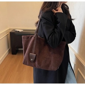 Detailed view of brown suede tote bag with leather shoulder strap on a female model