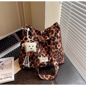 Detailed view of a leopard print canvas tote bag with a cute plush toast charm accessory