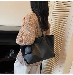 Close-up of black PU leather tote bag with round stitching and a small round coin purse