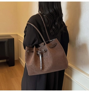 Close-up of brown vintage pleated tote bag with fine leather straps and metal buckle