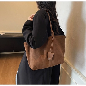 Close-up of brown suede tote bag featuring a leather water drop pendant and fine stitching