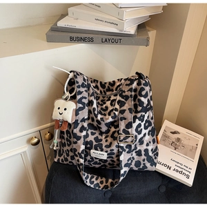 Leopard print tote bag with a toast plush charm placed on a blue striped stool