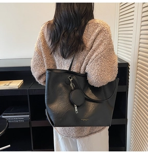 Detail of black tote bag with litchi texture grain and detachable coin purse accessory