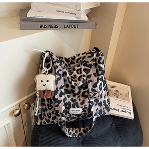 Detailed view of leopard print tote bag with plush toast charm on striped stool