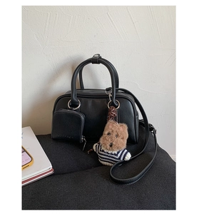 Close-up of black matte leather Boston bag with dog charm and detachable shoulder strap