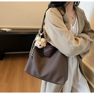 Détail du grand sac cabas marron foncé avec breloque chien en peluche et ruban