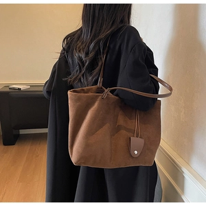 Detail of a large brown suede tote bag on shoulder with vintage matte finish