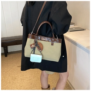 Close-up of canvas handbag with brown leather trim and metal turn-lock closure