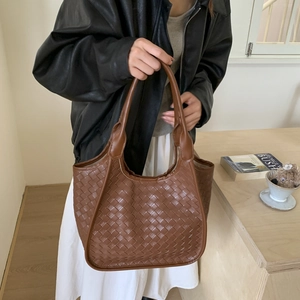 Close-up of brown woven leather texture on a spacious tote bag with shoulder strap