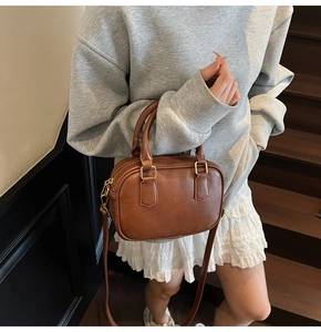 Detail of vintage brown leather Boston bag with gold zippers and adjustable strap