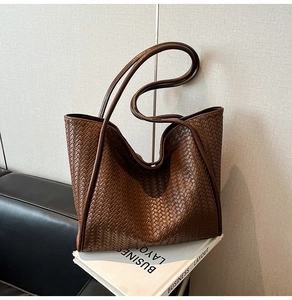 Detail of a brown woven leather tote bag featuring handcrafted Intrecciato weave design