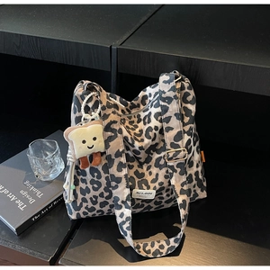 Detail of leopard print canvas tote bag with adjustable strap and cute plush pendant