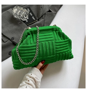 Detail of green knitted clutch bag with thick weave texture and silver chain strap