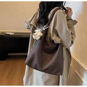 Détail du sac fourre-tout marron foncé mat avec un joli pendentif chiot en peluche