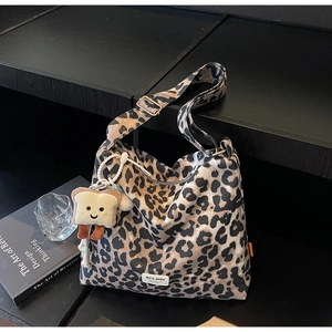 Detail of leopard print tote bag with adjustable strap and plush bread charm accessory