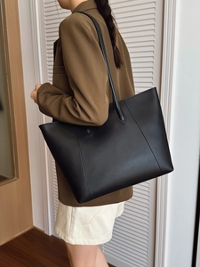 Side view of a large black matte leather tote bag on a model for a business look