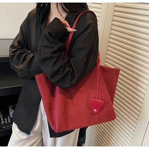 Detail of red faux suede tote bag featuring a triangle tag on a black shirt model