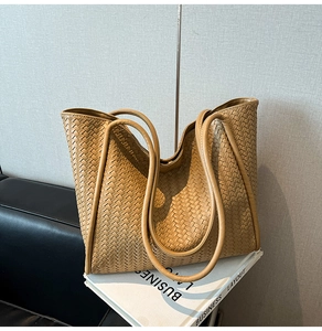 Close-up of caramel woven leather tote bag texture with reinforced shoulder straps
