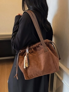 Brown suede bucket bag with drawstring closure and decorative wooden beads on shoulder strap