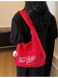 Large red canvas tote bag with embroidery, featured in a natural indoor lifestyle scene
