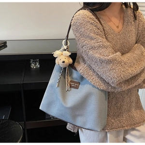 Détail du sac à bandoulière en toile avec garniture en cuir brun et breloque chien