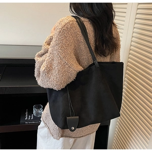 Detail of black suede tote bag featuring a leather card holder charm on a model