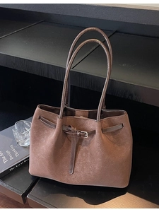 Vintage brown leather tote bag with pleated detail and adjustable straps on wooden shelf
