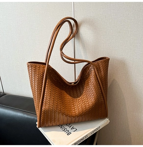 Close-up of brown woven leather texture on a large tote bag with dual shoulder straps