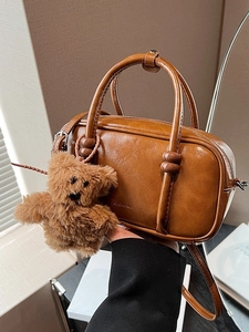 Vintage brown leather bowling bag with top handles and a cute plush bear charm