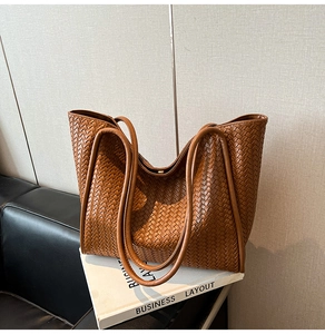 Close-up detail of vintage brown woven tote bag showing luxury texture and leather straps