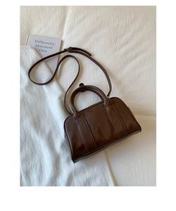Detail of a minimalist dark brown Boston bag with smooth faux leather on a white background
