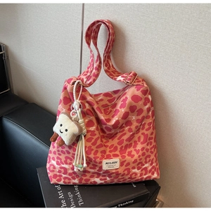Detail of pink leopard print tote bag featuring a plush charm and adjustable wide strap
