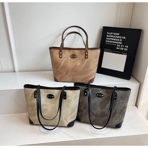 Detailed view of large leather tote bags in brown, beige, and grey on a display stand