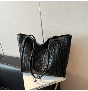 Close-up detail of high-quality black woven leather texture on a spacious tote bag