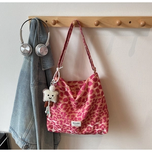 Pink leopard print tote bag with plush charm and branding patch on casual hook