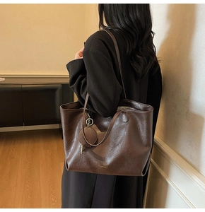 Detail of deep brown tote bag on model showing large capacity and smooth leather texture