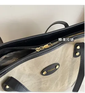 Detail of smooth metal zipper and leather trim on a canvas tote bag for daily commute