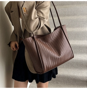 Detail of dark brown woven tote bag showing the large Intrecciato weave texture and thin straps