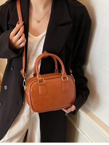 Caramel brown vintage crossbody bag with dual handles and gold hardware shown on a model