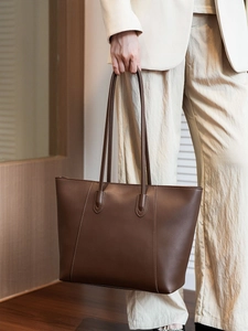 Detailed close-up of dark brown leather tote bag with vertical stitching and slim straps