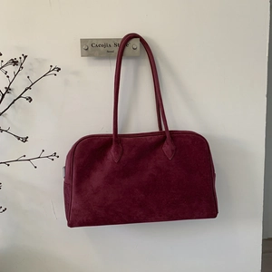 Gros plan détaillé d'un sac fourre-tout en daim rouge foncé avec une texture douce
