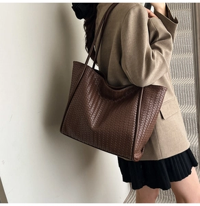 Close-up of the vintage woven leather texture on a dark brown oversized tote bag