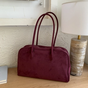 Détail d'un sac cabas en daim bordeaux avec fermeture éclair sur une table en bois