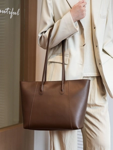 Detail view of large brown leather tote bag with elegant vertical stitching and long straps