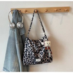 Leopard print tote bag hanging with cute plush pendant and wide shoulder strap detail