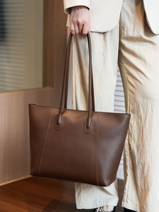 Detail of dark brown leather tote bag with vertical stitching and long shoulder straps