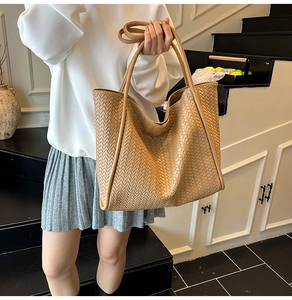 Detailed view of khaki woven texture and leather straps on this large tote bag