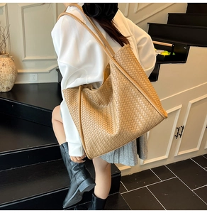 Detail of a large woven leather tote bag shown in a minimalist interior setting
