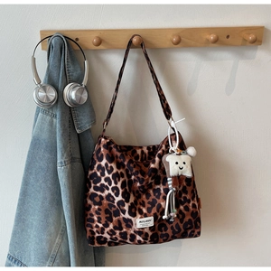 Detailed view of leopard print shoulder tote bag with a cartoon toast charm and logo label